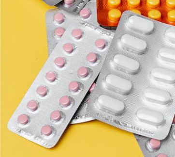 Multiple blister packs of pink, white, and orange pills on a yellow background.
